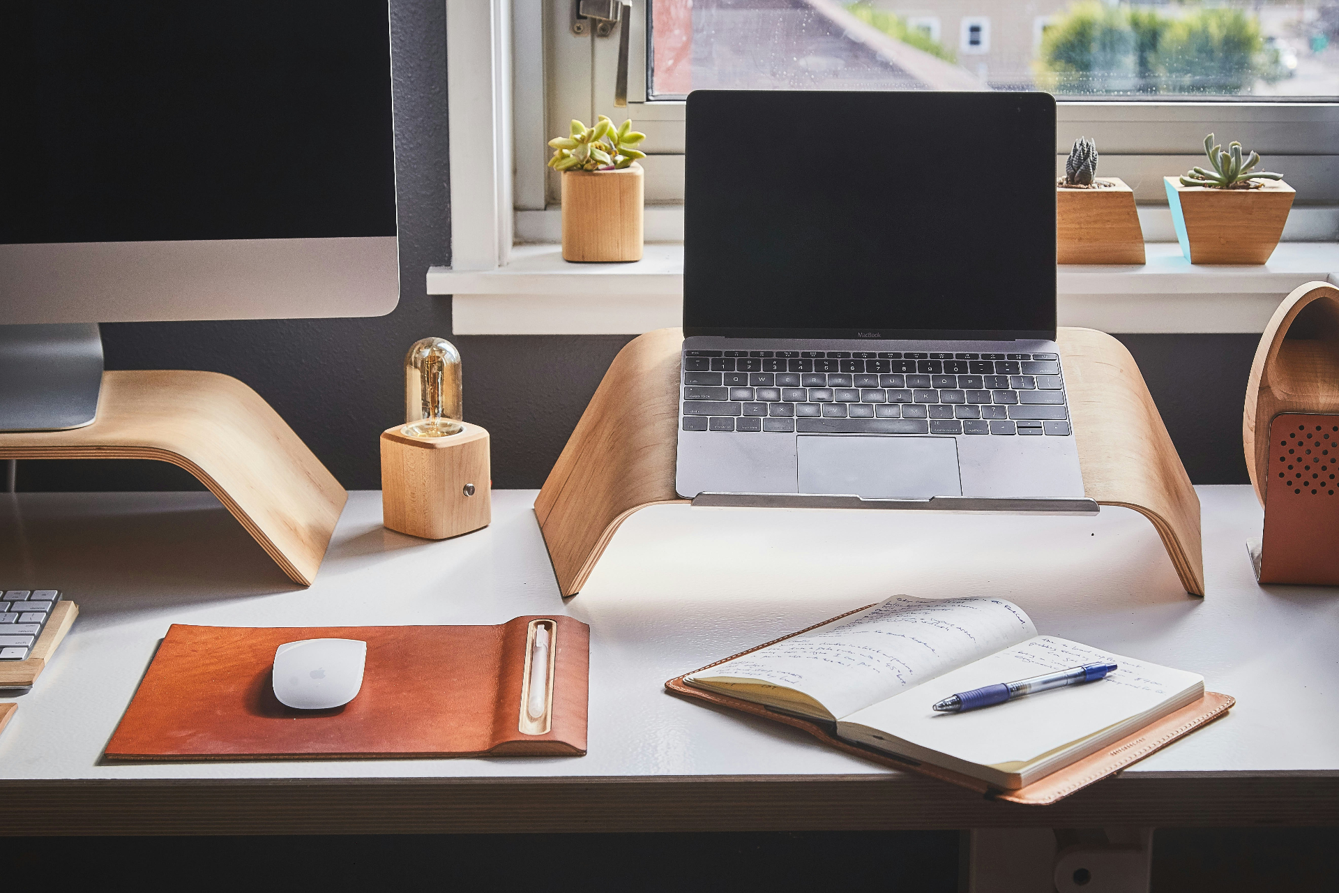 Espace de travail soigné : ordinateur portable, carnet de notes, lampe et plantes